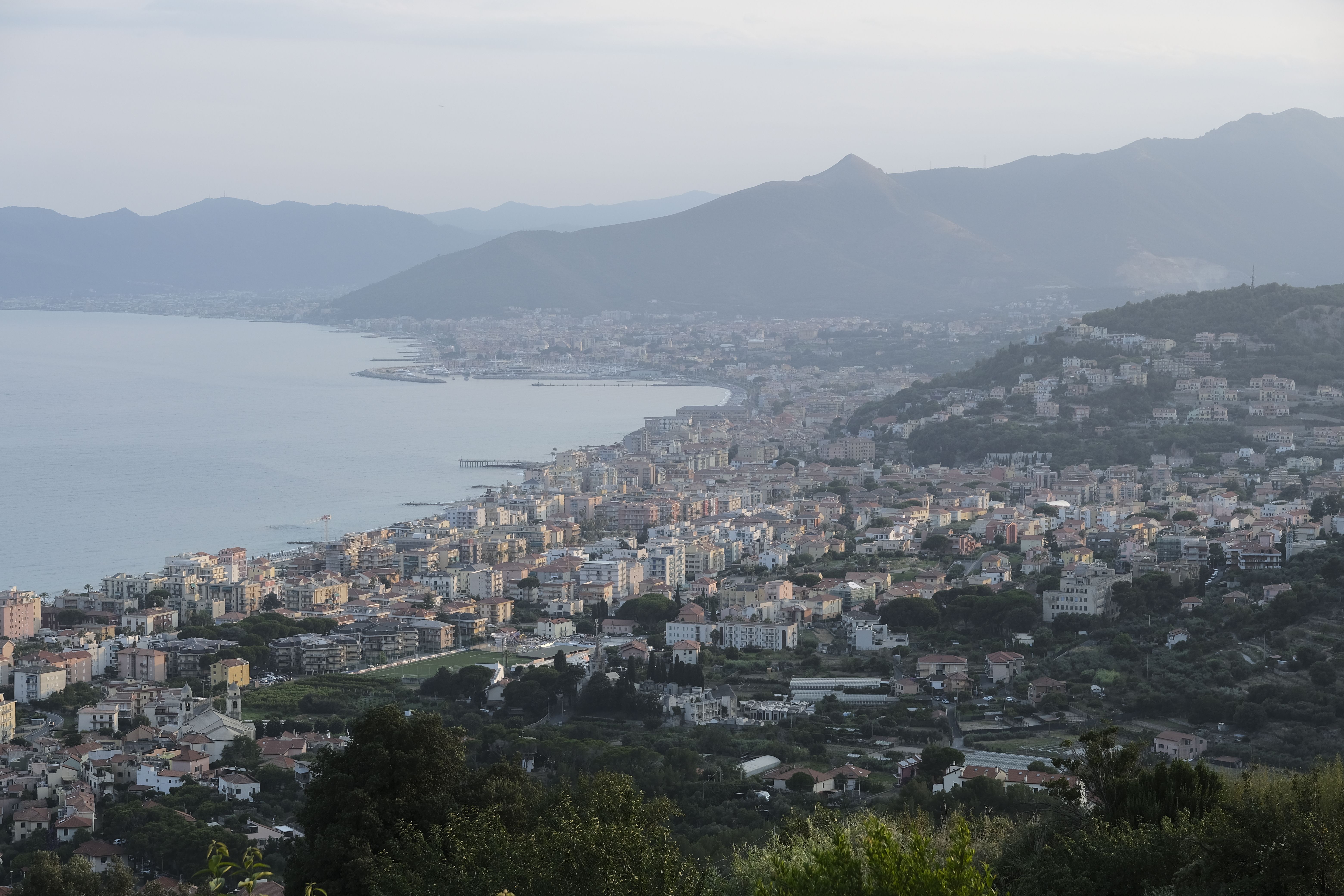 A breathtaking view of a coastal city in Italy with mountains and sea in the background.