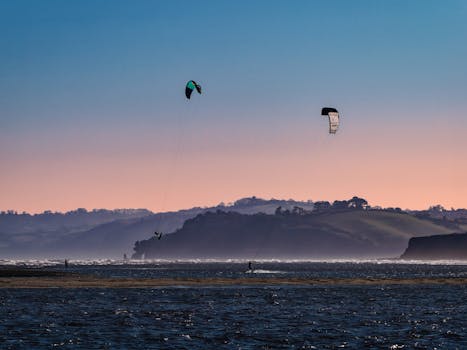 Vibrant kitesurfing scene at sunset on Exmouth beach, capturing dynamic water sports in beautiful coastal landscape.