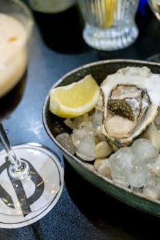Top view of a fresh oyster served with a lemon wedge on ice, perfect for seafood lovers.