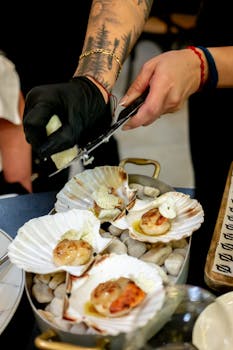 Chef preparing a gourmet scallop dish with exquisite presentation in a fine dining restaurant.