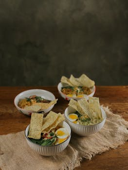 Delicious Asian noodle soup bowls with boiled eggs and crispy crackers on a rustic table