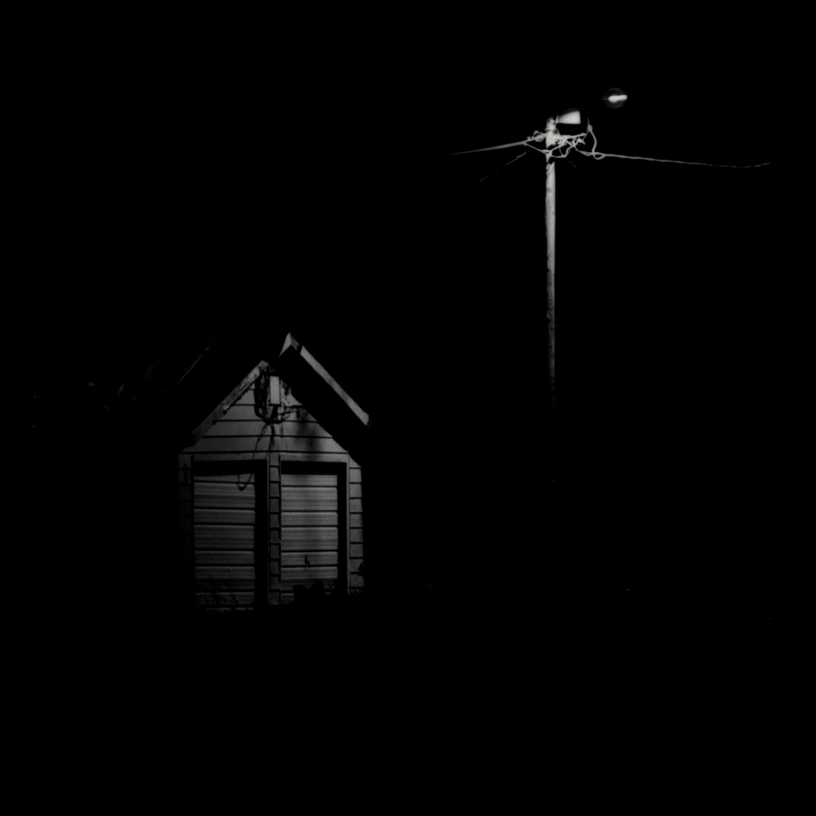 A dramatic black and white photo of a cottage under streetlight glow in Illinois.