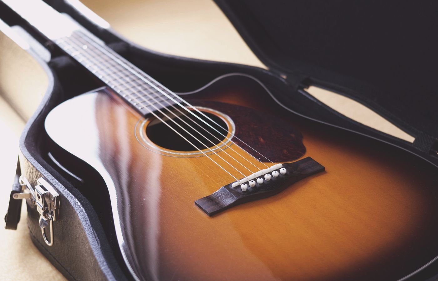 A close-up photo of a vintage acoustic guitar in a hard case, showcasing its elegant design and wood grain.