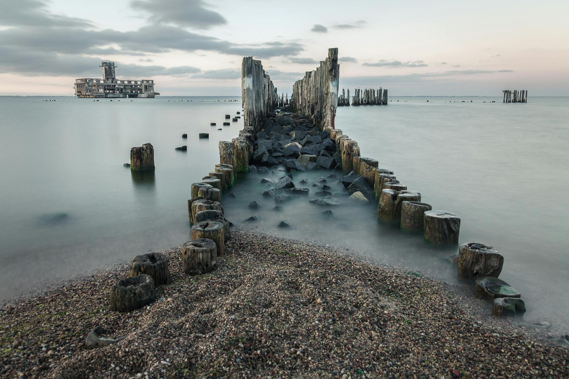 Tranquil Baltic Sea landscape in Gdańsk with historic ruins and calm waters at sunrise.