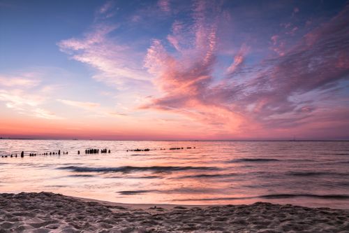 Free Capture the serene beauty of a Gdańsk beach at sunset with vibrant pink and orange skies. Stock Photo