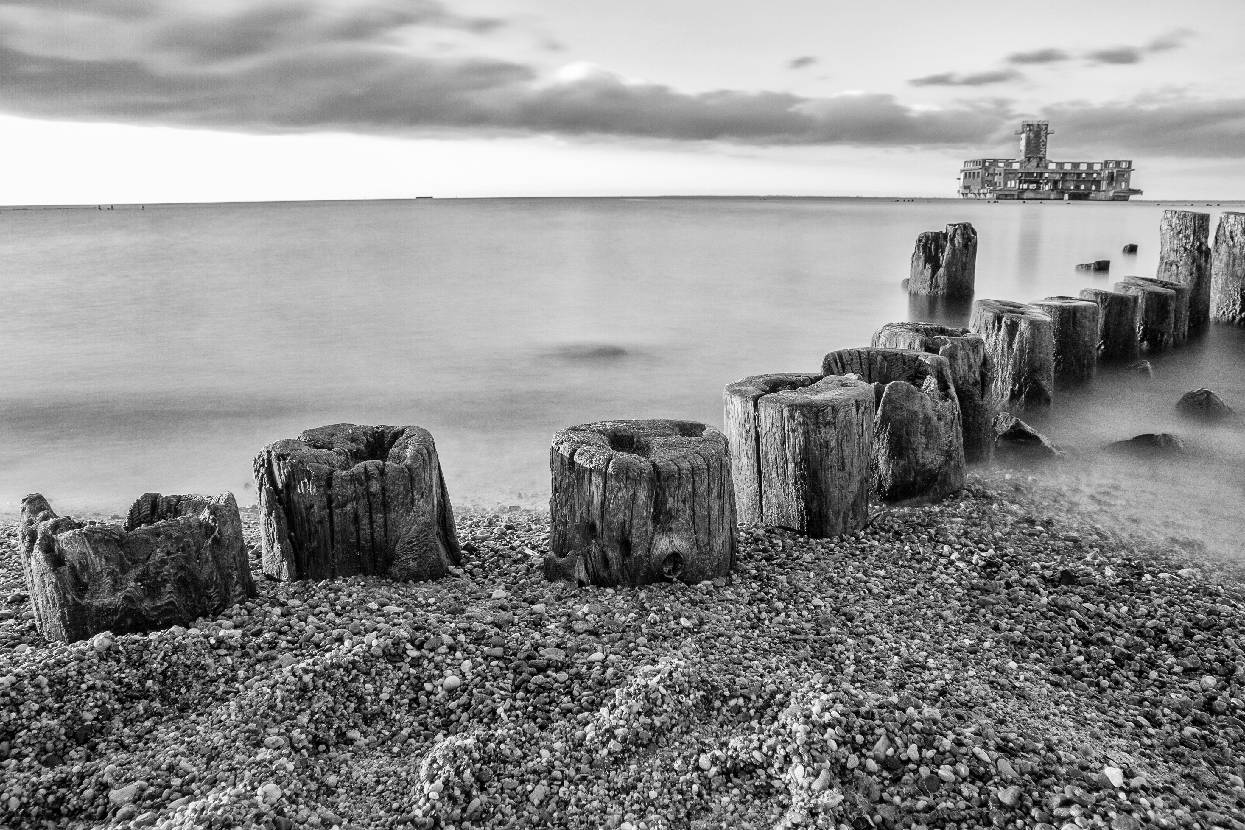 Monochrome view of Baltic Sea shoreline with Tenth Torpedo Station ruins in Gdańsk.