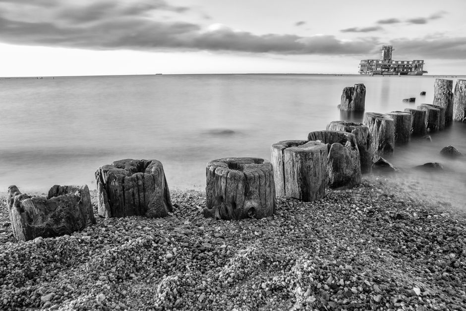 Monochrome view of Baltic Sea shoreline with Tenth Torpedo Station ruins in Gdańsk.
