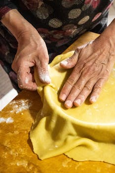 Close-up of hands shaping fresh pastry dough with a rustic feel, ideal for baking enthusiasts.