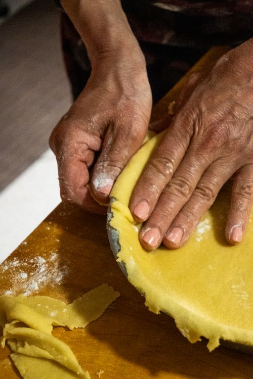 Free Hands expertly shaping dough for pie crust on a wooden table, highlighting home cooking. Stock Photo