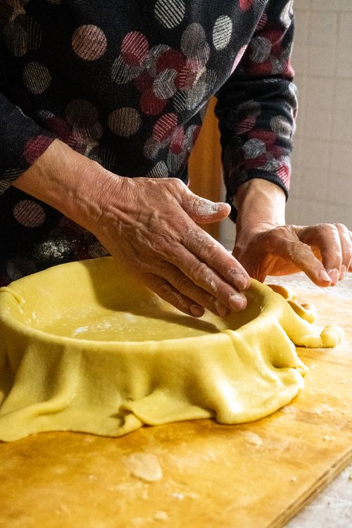 Free Person's hands preparing a fresh pie crust on a wooden surface. Stock Photo