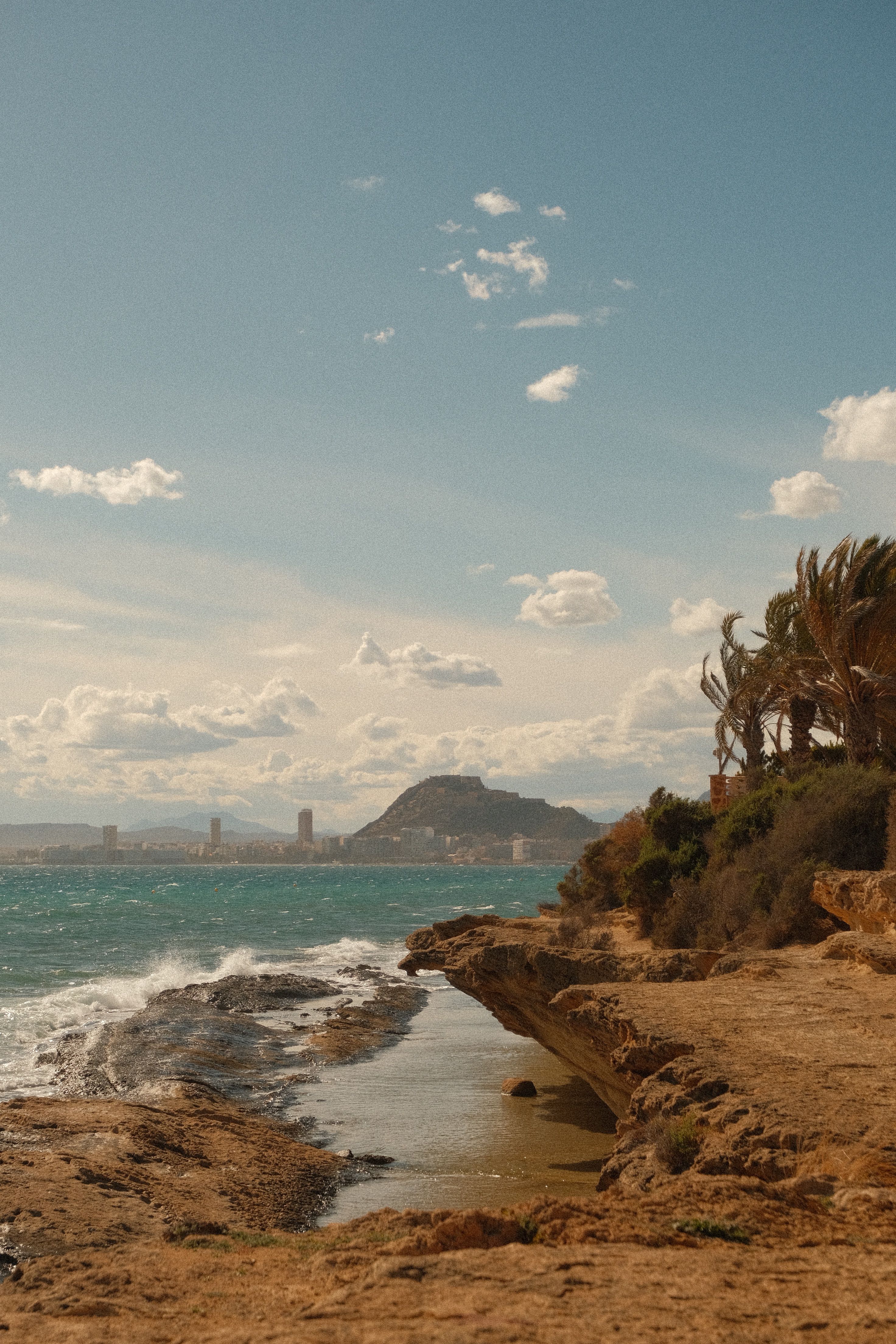 Beautiful shoreline view with the iconic Mount Benacantil in Alicante, Spain, under a clear sky.