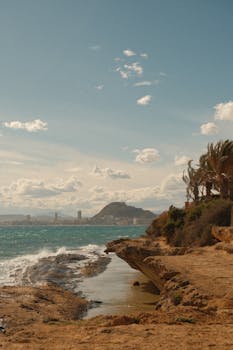 Beautiful shoreline view with the iconic Mount Benacantil in Alicante, Spain, under a clear sky.