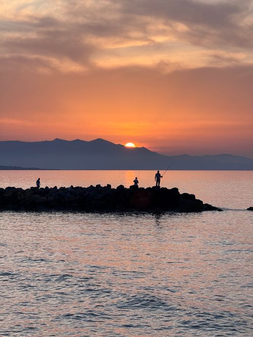Free Silhouettes fishing during a stunning sunset over the sea in Crete. Stock Photo