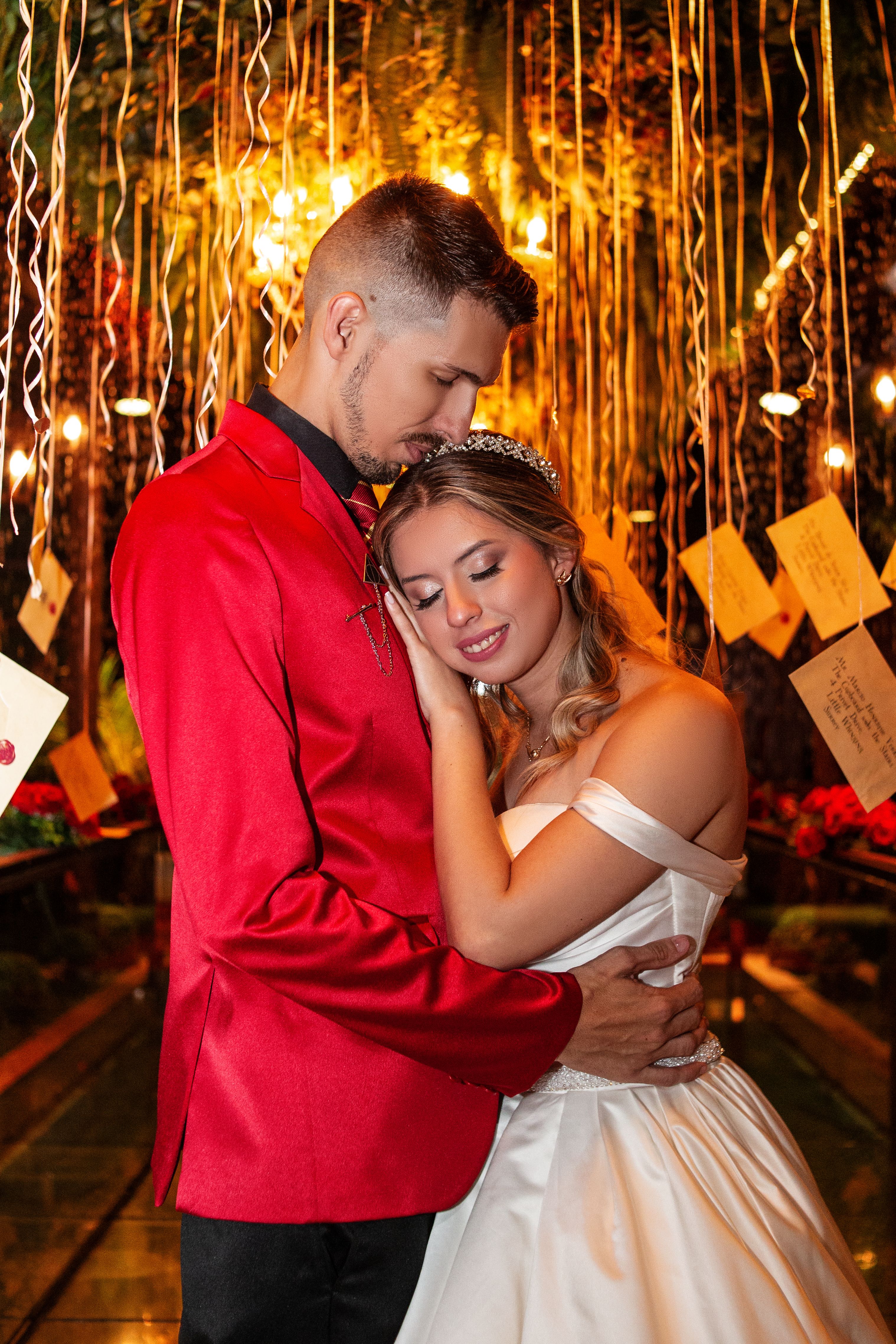 A bride and groom lovingly embrace under decorative lighting in a festive setting.