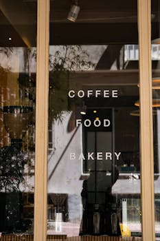 Café window with reflections, showcasing 'COFFEE FOOD BAKERY' in Istanbul, Turkey.