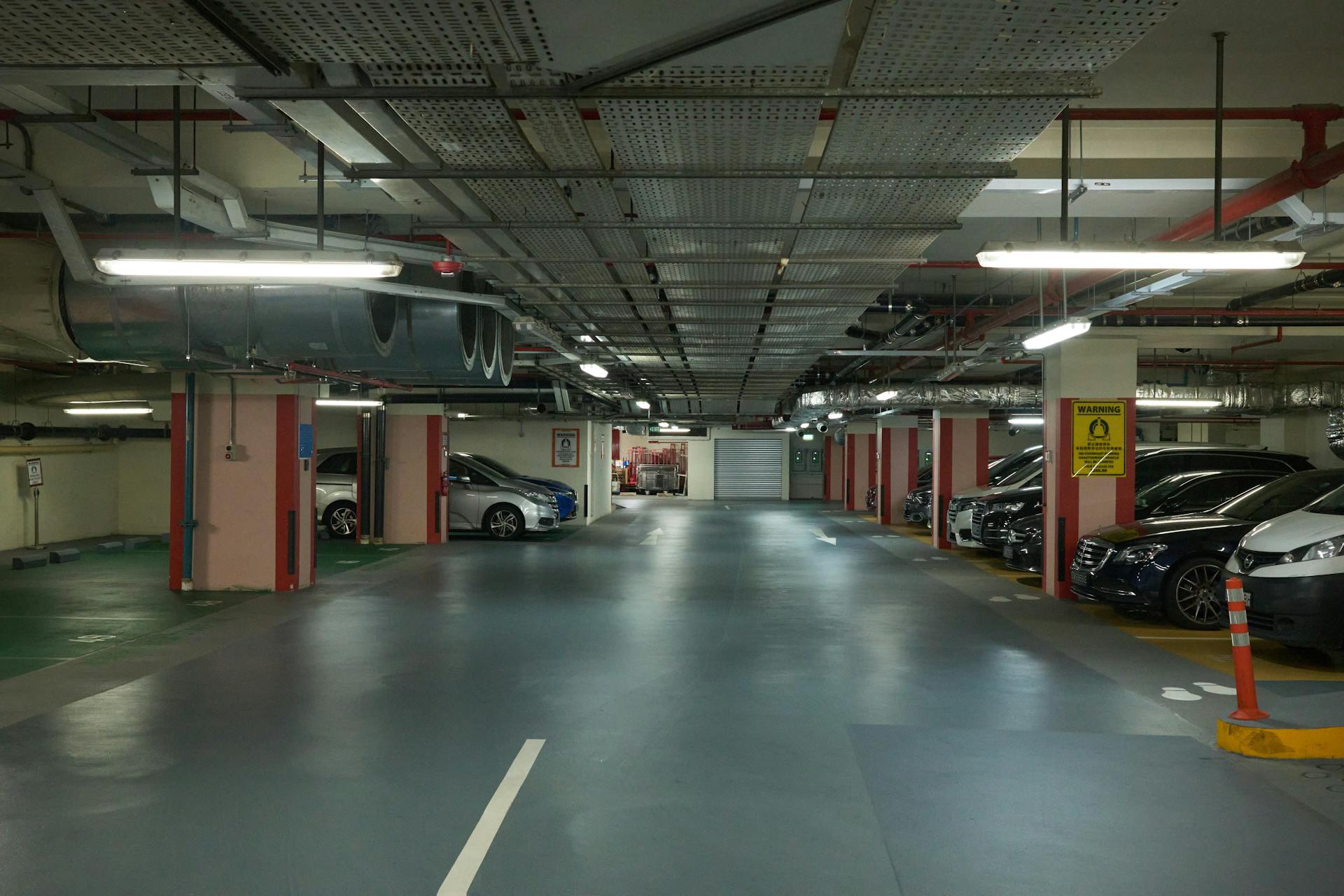 Wide view of a dimly-lit underground parking garage filled with modern cars.