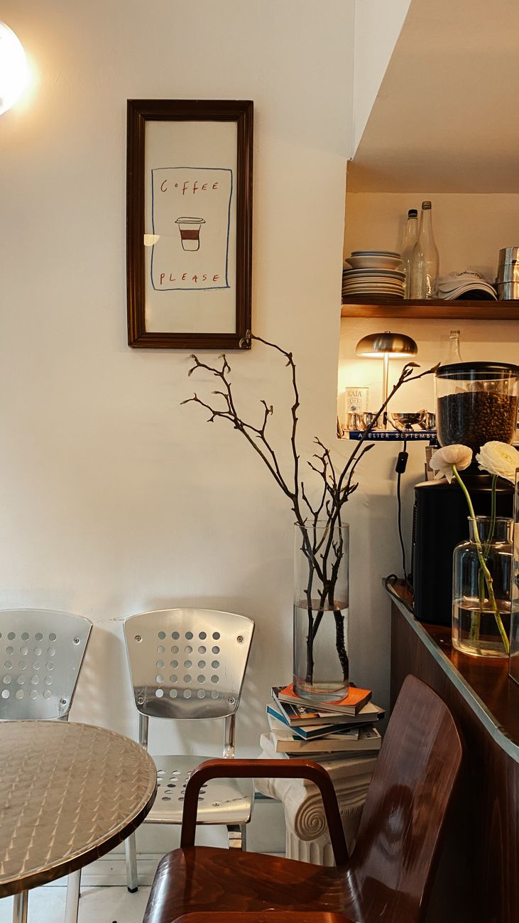 Warm cafe interior with minimalist decor featuring a coffee-themed artwork and cozy seating.