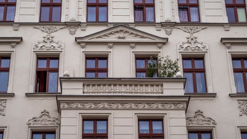 Free Ornate European building facade featuring detailed stonework and red-framed windows. Stock Photo