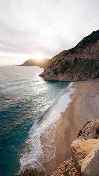 Breathtaking view of a rocky coastline at sunset with waves gently crashing ashore.