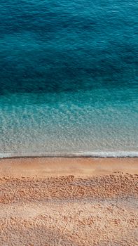 A serene beach scene featuring gentle waves meeting soft sandy shores under a clear sky.
