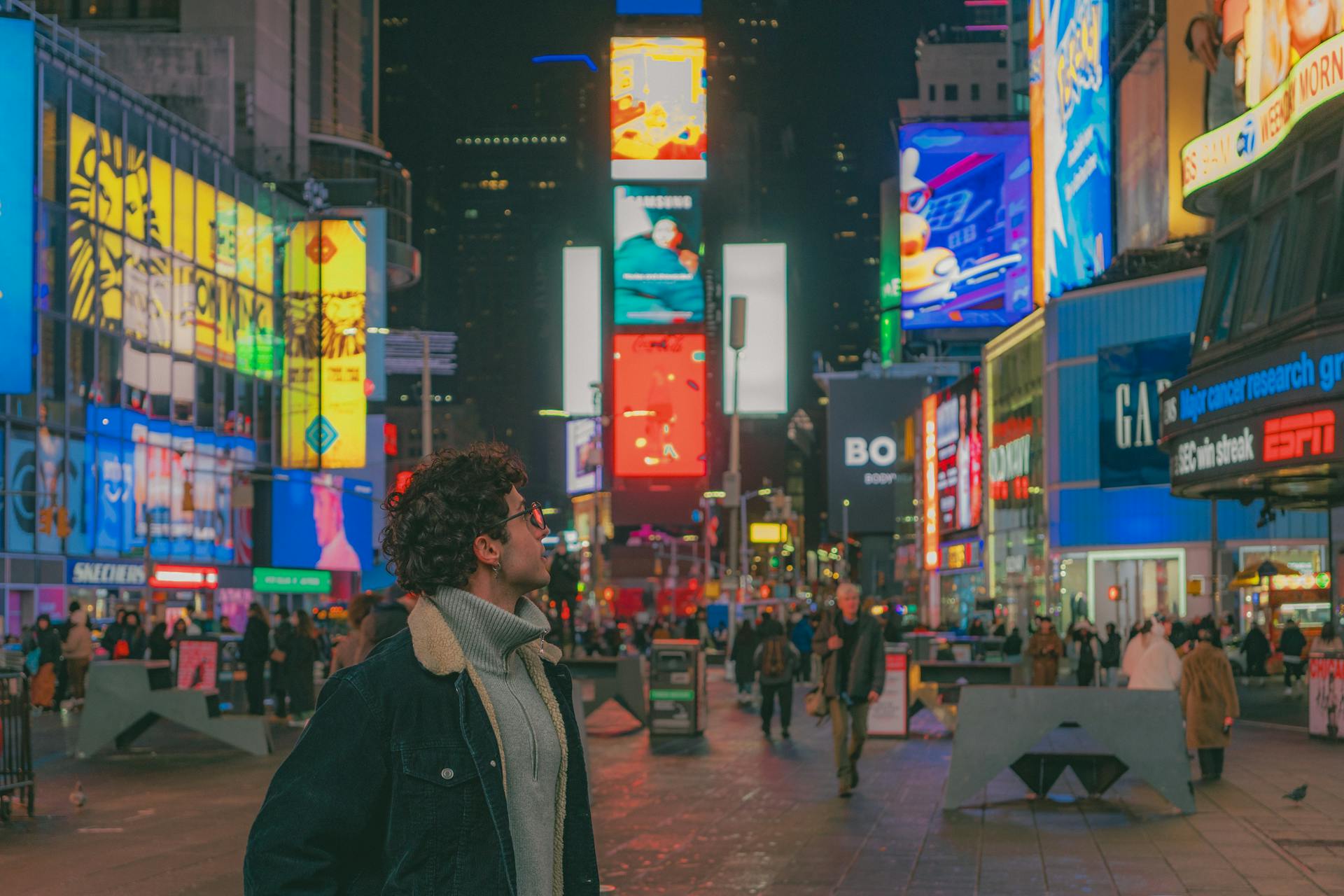 Explore the bustling energy of Times Square at night with vibrant lights and diverse crowds.
