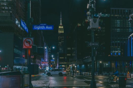 Atmospheric night scene of Eighth Avenue with the Empire State Building in New York City.
