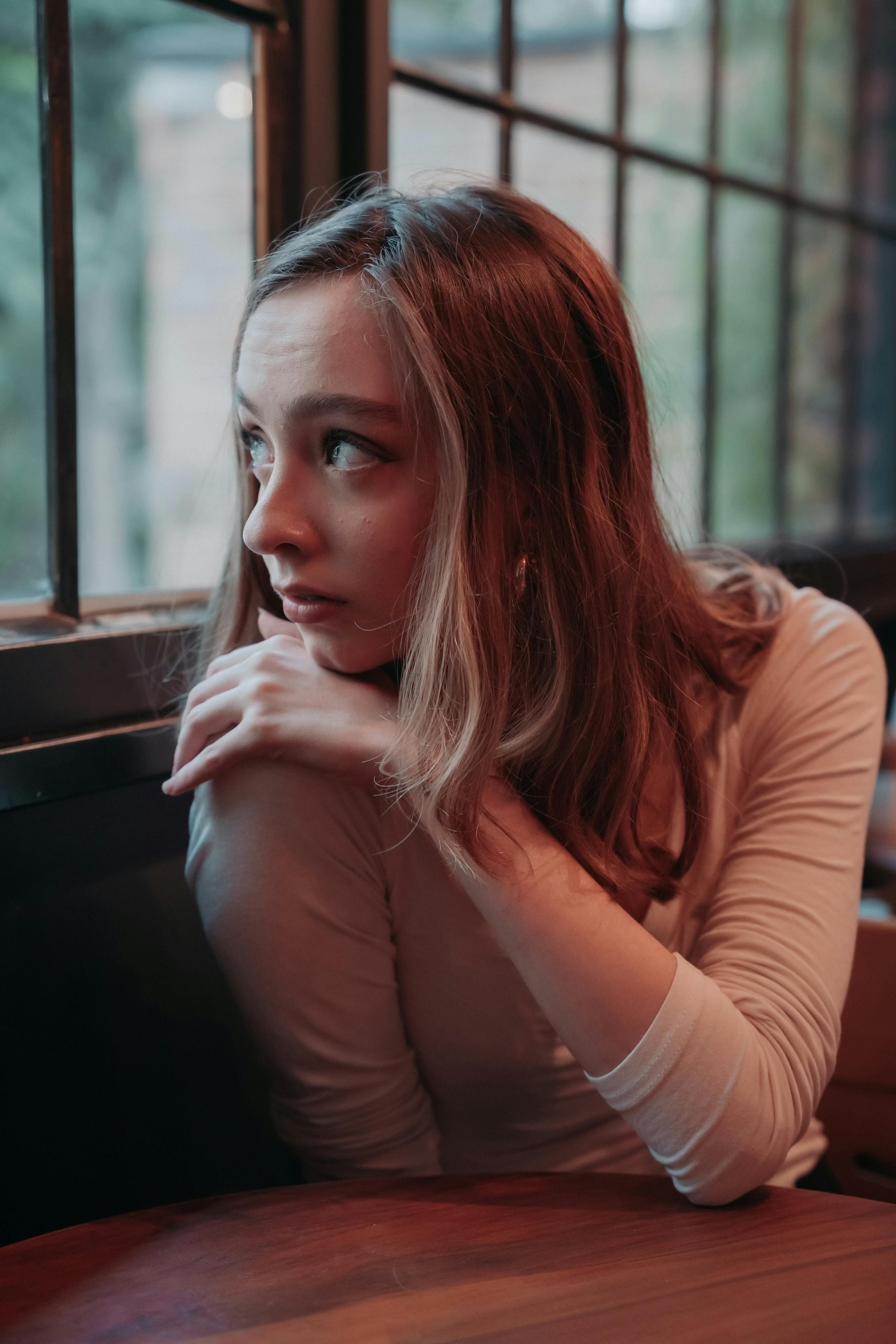 Pensive young woman gazing out from a cafe window