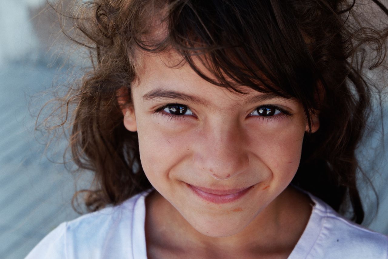 charming close up portrait of a smiling young girl with curly hair