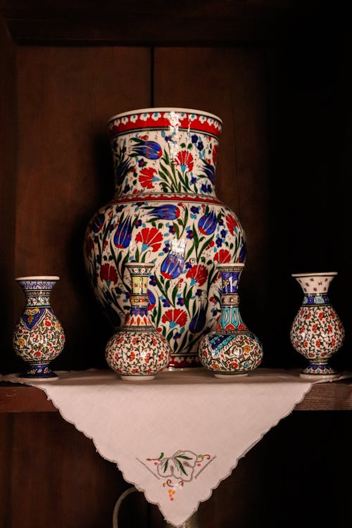 Free A vibrant display of floral-patterned ceramic vases on a wooden shelf. Stock Photo