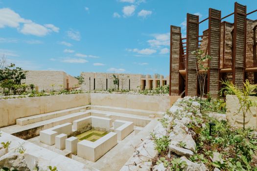 Explore modern architectural elements with a geometric water feature under a sunny sky in Tulum, Mexico.