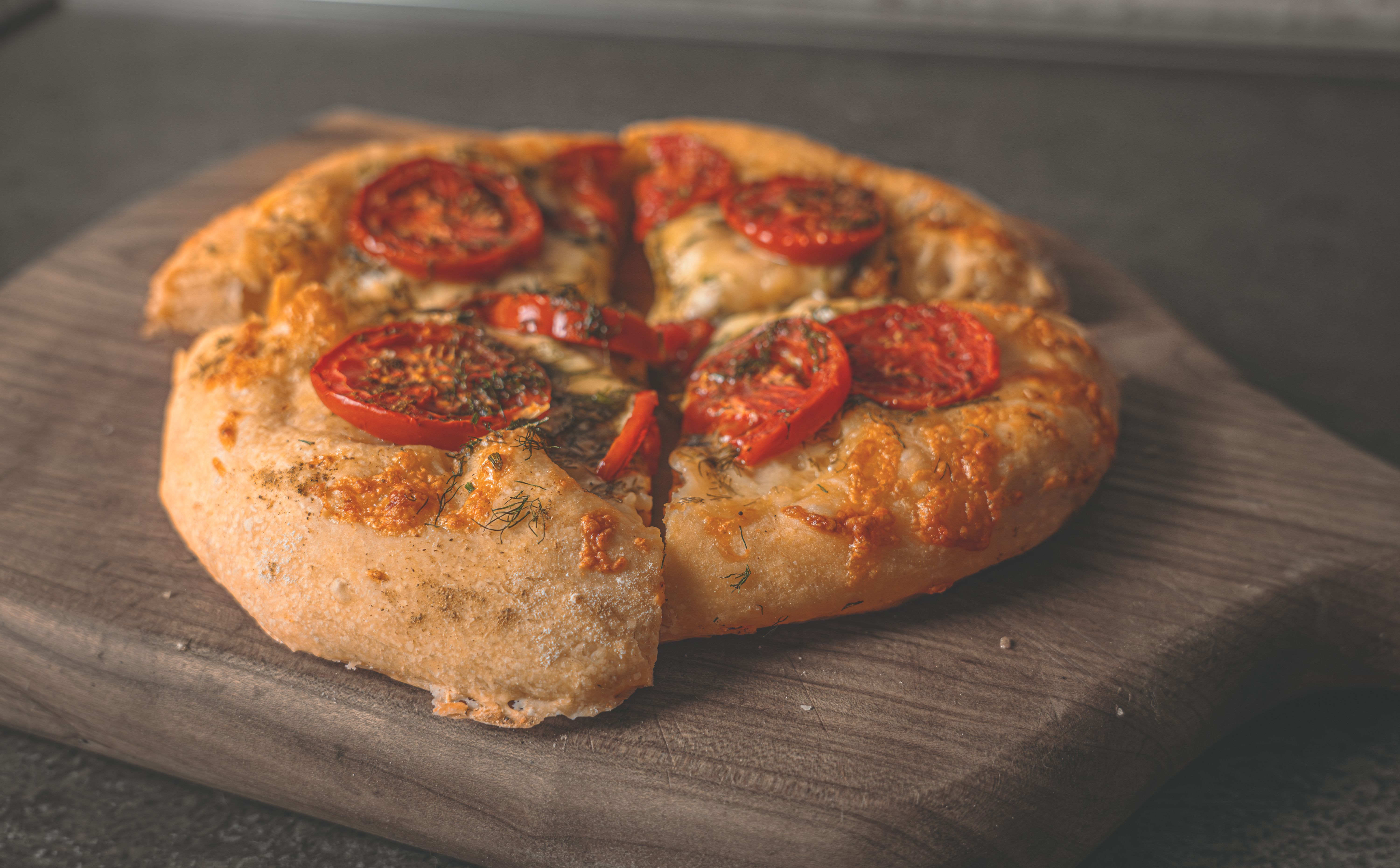 Tasty homemade pizza topped with fresh tomatoes and cheese on a wooden board.