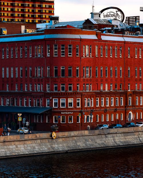 Free A vibrant red brick building along the riverside under a clear sky in an urban setting. Stock Photo