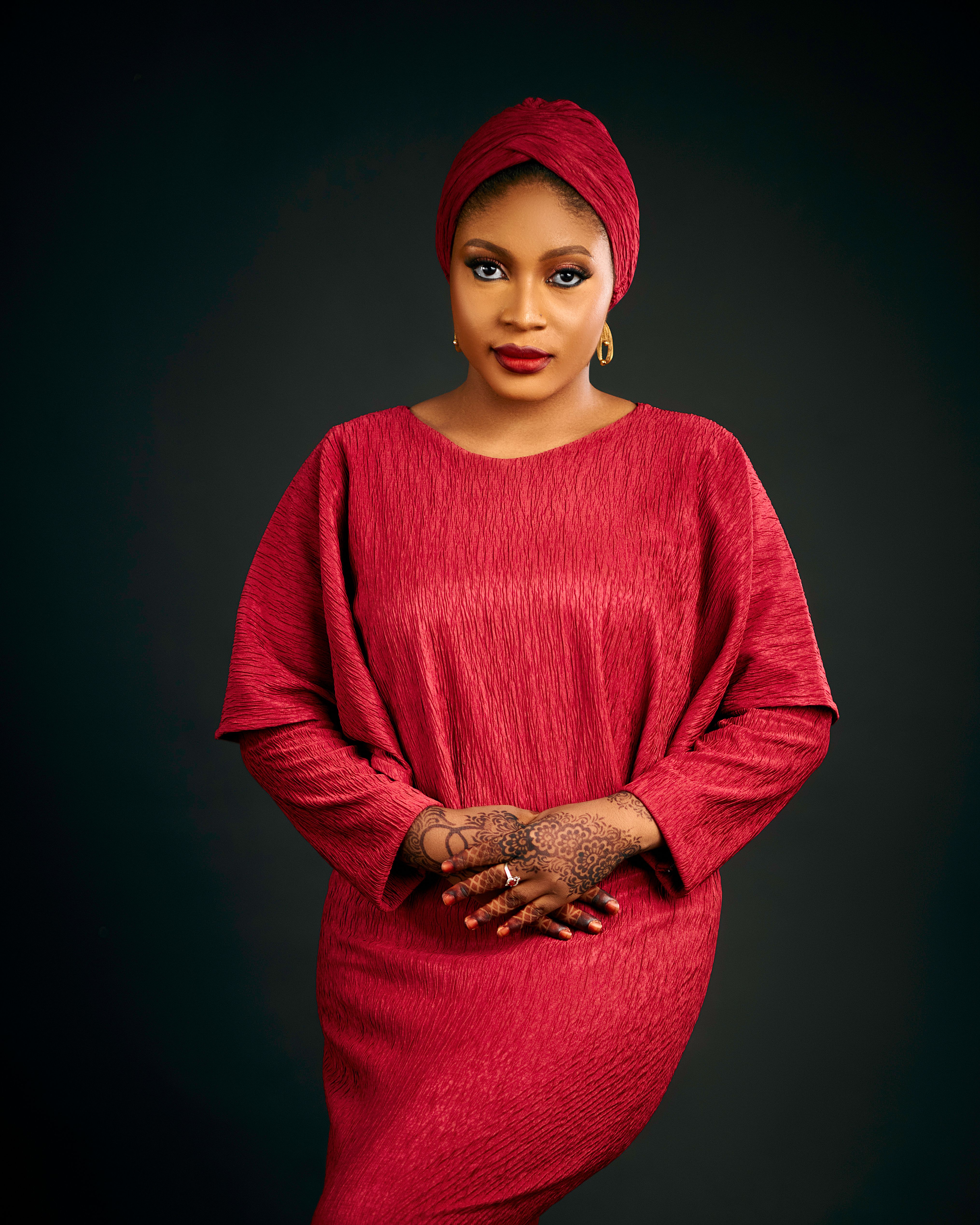 Portrait of a woman in a red dress showcasing henna designs and a serene expression.