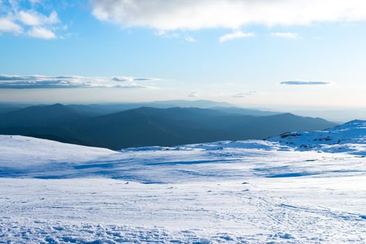 Vast snowy terrain with distant mountain views under a clear blue sky in Serra da Estrela, Portugal.