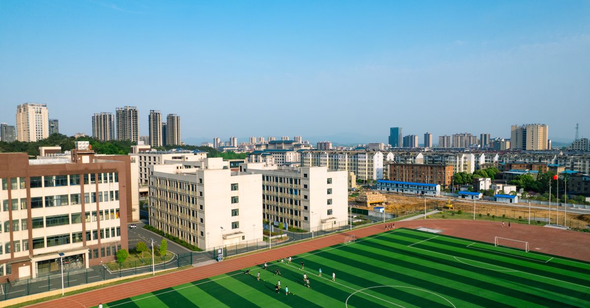 Aerial shot displaying a soccer field amidst urban buildings with a city skyline.