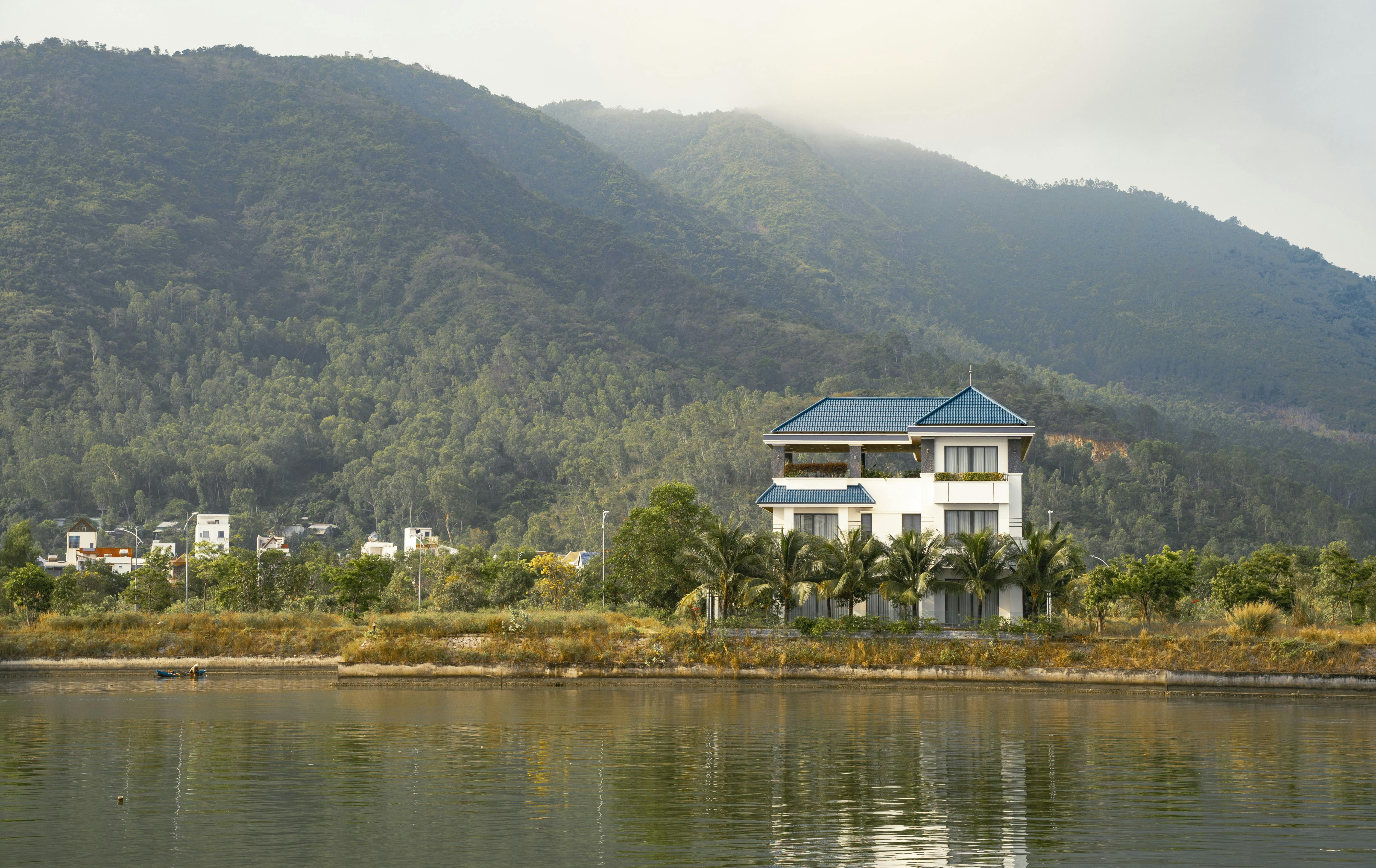 A picturesque house by a tranquil lake with a mountain in the background, offering a serene getaway.