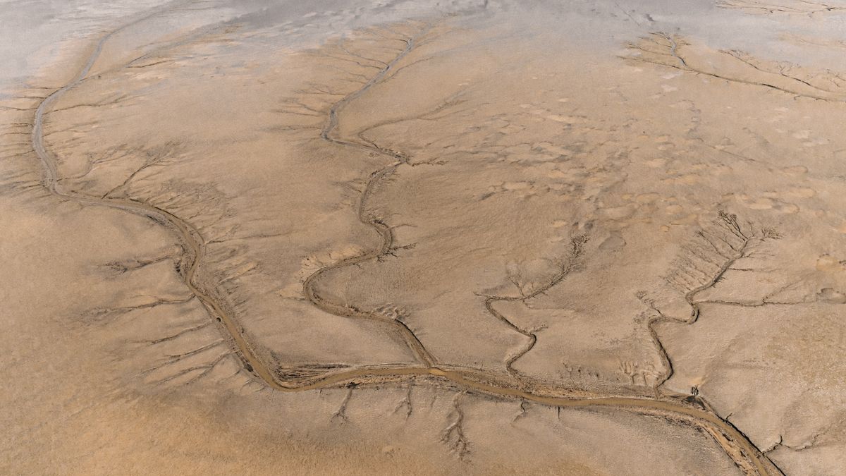 Aerial view of a dry riverbed cutting through desert landscape, showing the effects of drought on water supply