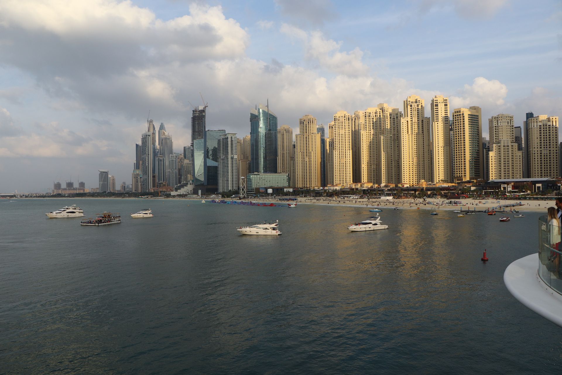 Breathtaking view of Dubai Marina's skyline with luxurious boats and clear waters during daytime.