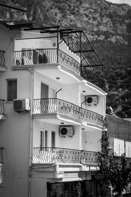 Free Black and white photo of a modern apartment building with balconies against a mountain backdrop. Stock Photo