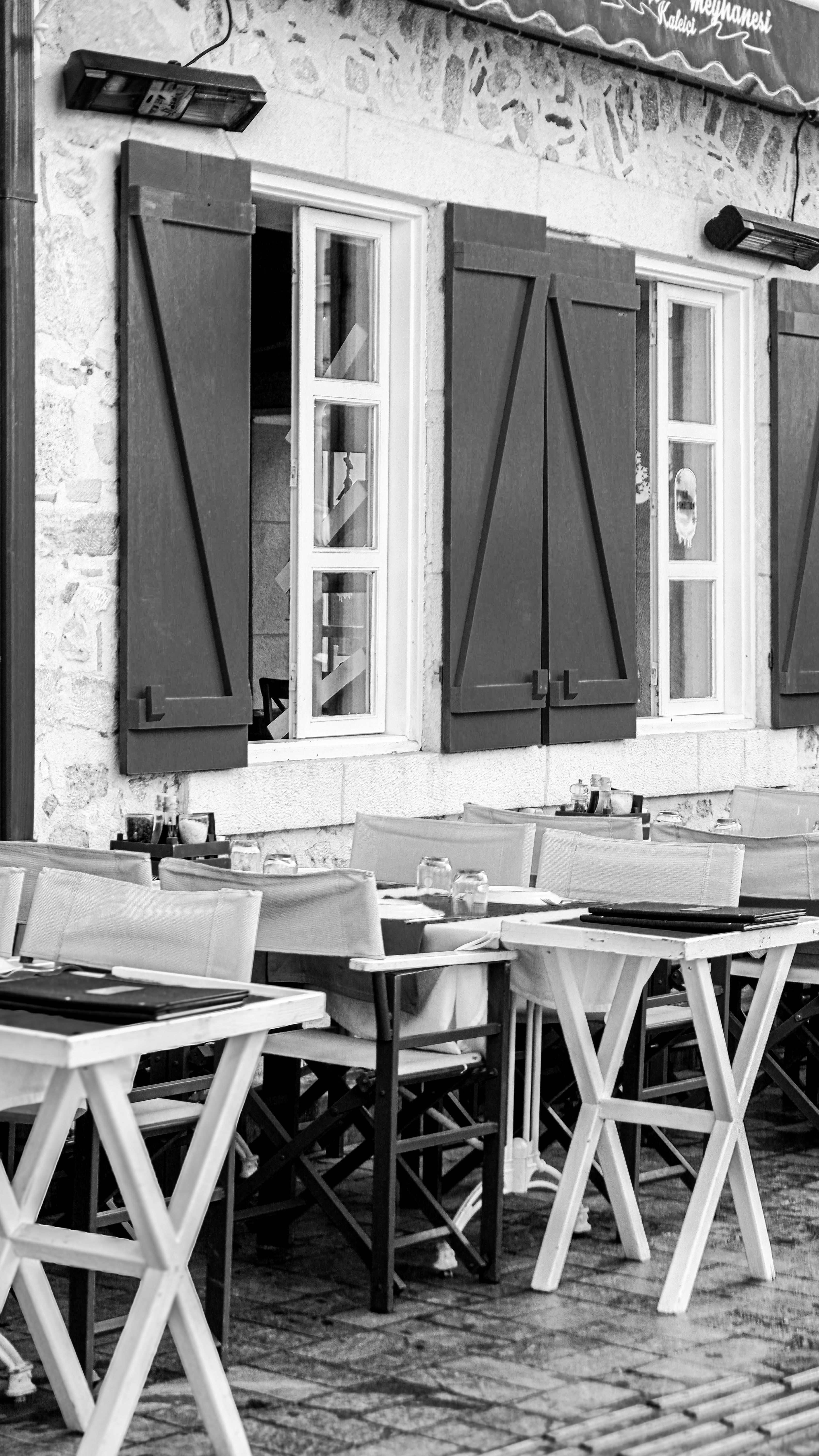 Explore the charm of this outdoor cafe with rustic shutters and cobblestone patio.