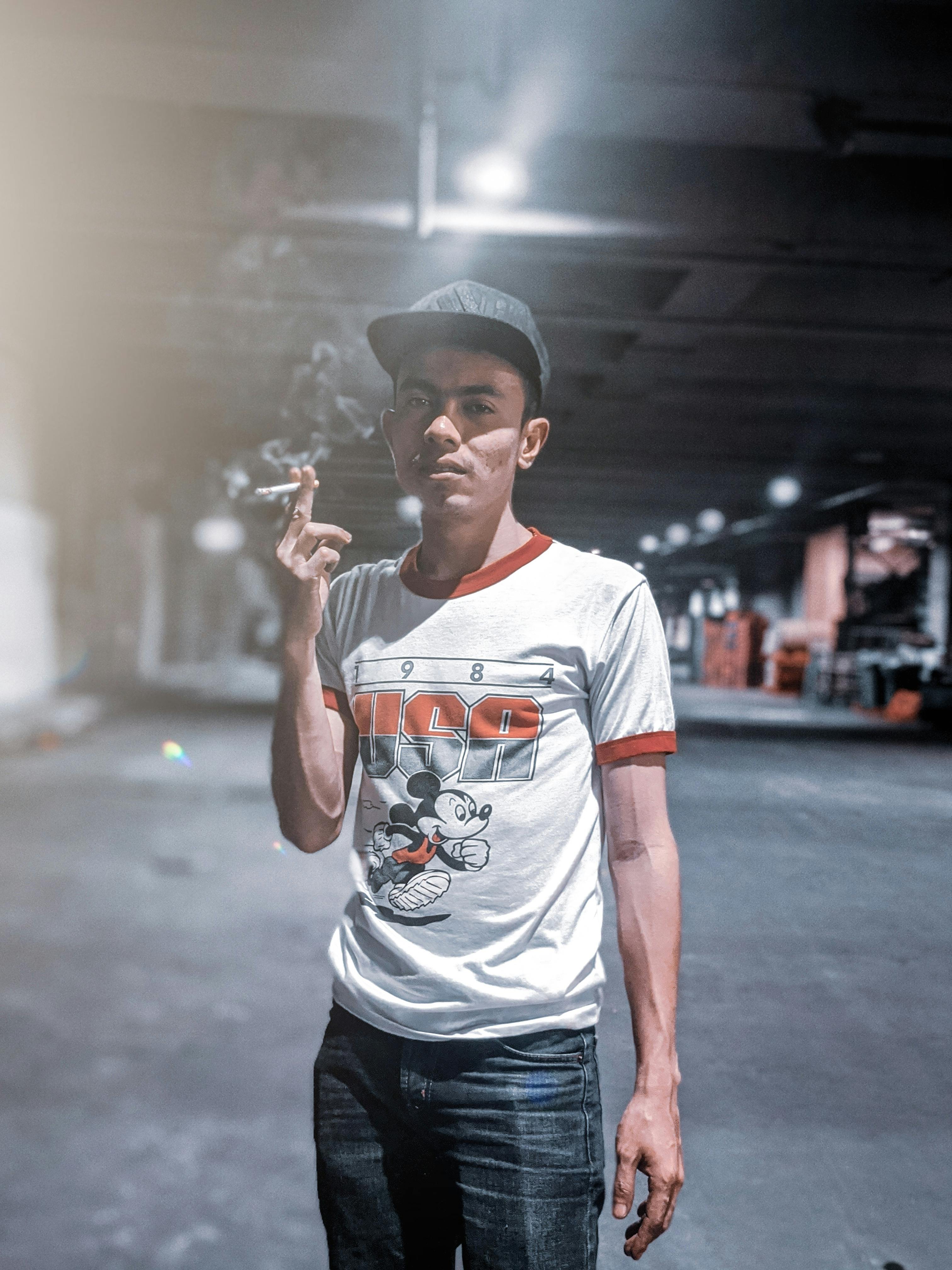 man wearing orange and white shirt holding cigarette smoking