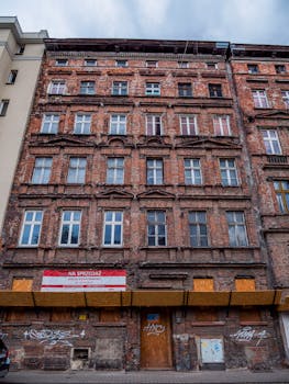 Old multi-story brick building with urban charm, featuring a 'For Sale' sign.
