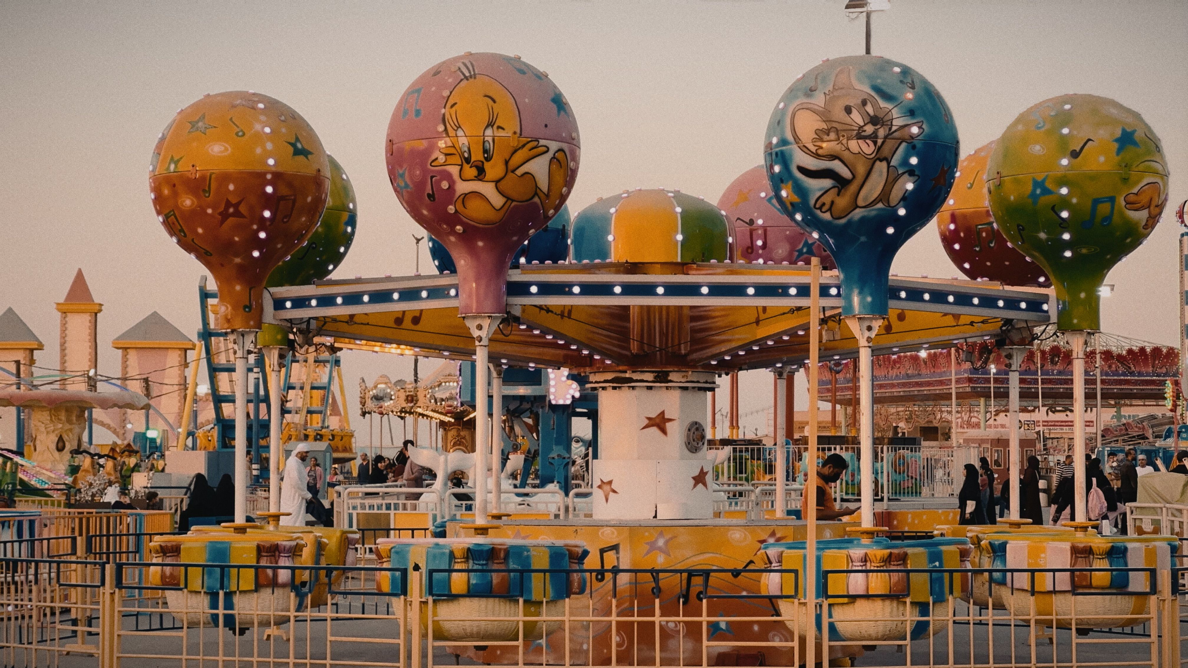 A whimsical carousel ride featuring cartoon characters at a lively amusement park.