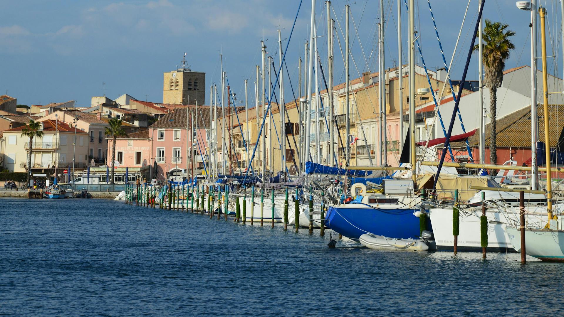 Vibrant harbor scene in Mèze, Occitanie, France with boats docked along the waterfront.