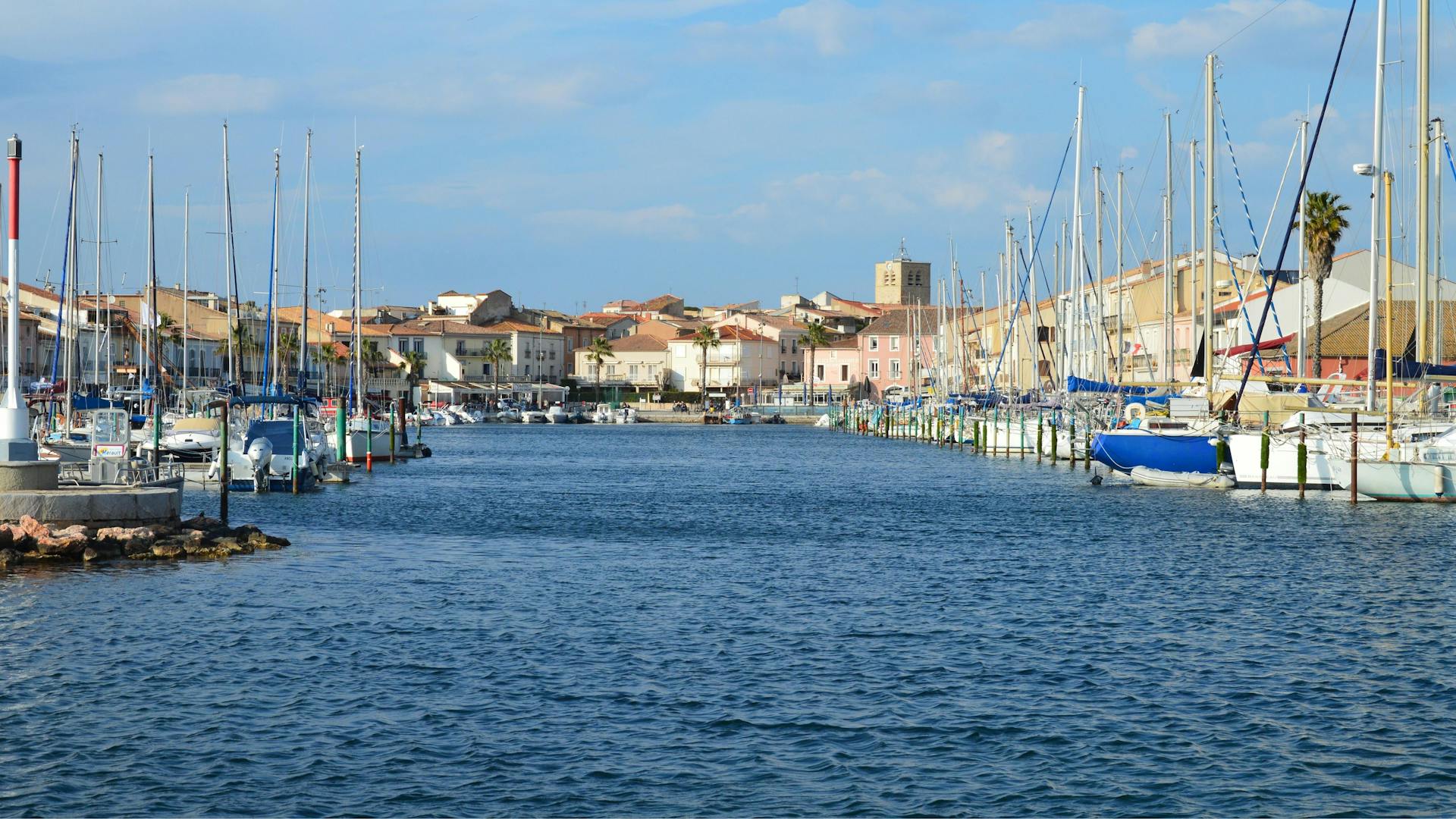 Vibrant harbor scene in Mèze, Occitanie with boats and picturesque waterfront buildings.