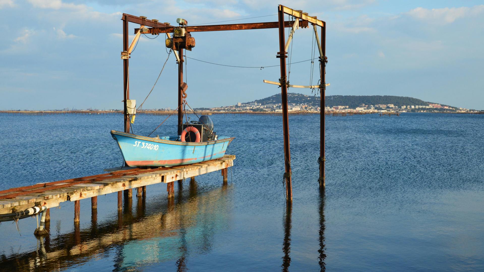 Scenic view of a rustic boat dock and blue boat in Bouzigues, France.