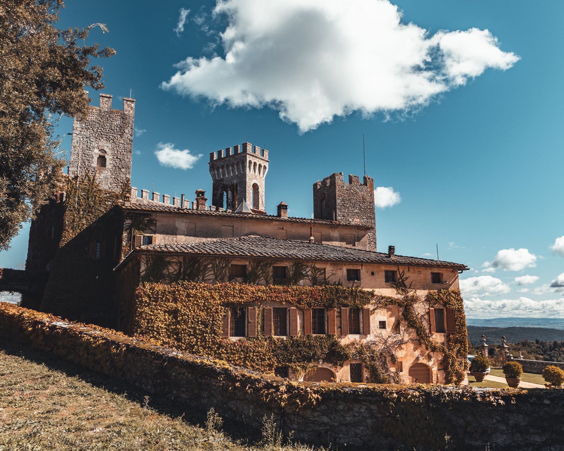 A picturesque medieval castle with towers and ivy-covered walls under a blue sky.