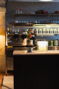 A warmly lit cafe counter with a coffee machine and decor details.
