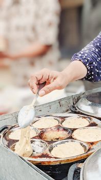 Close-up of Indonesian street vendor preparing traditional cakes outdoors in Tegal.