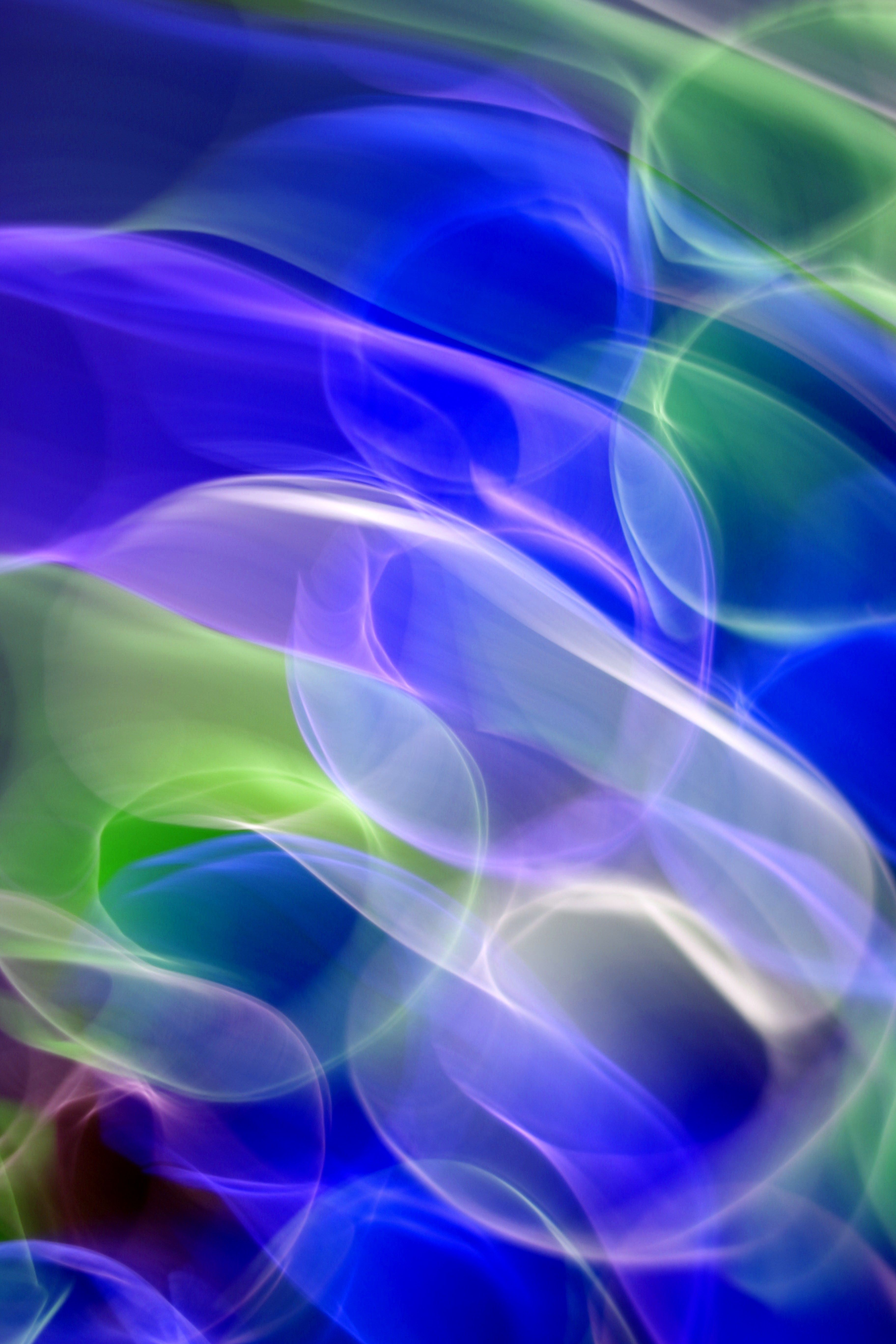 Vibrant abstract waves of blue, green, and purple light creating a sense of fluid motion.